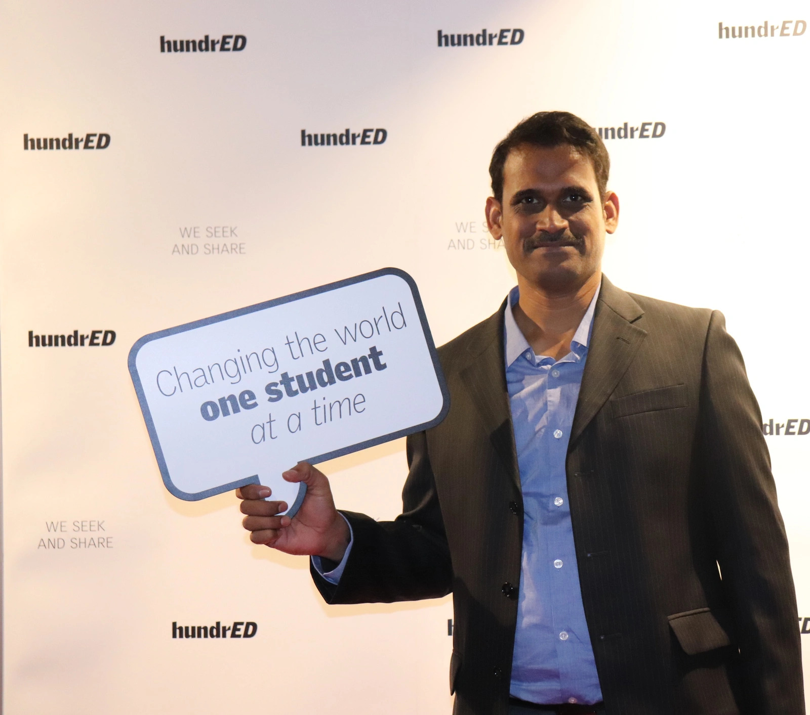 JR Yeruva holding sign "Changing the world one student at a time" at HundrED
